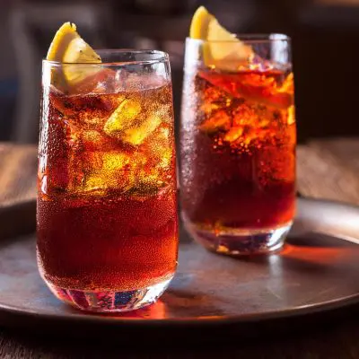 Close-up of two Americano cocktails in ice-filled highball glasses with lemon garnish