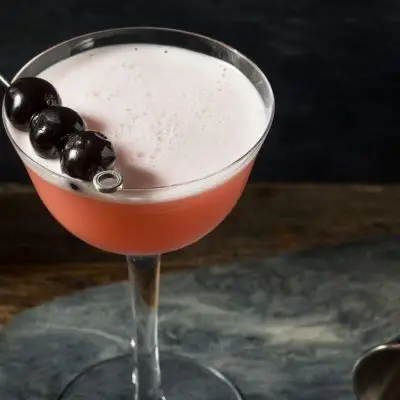 A refreshingly boozy Pink Lady cocktail garnished with Luxardo cherries