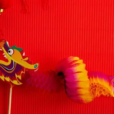 Red backdrop with a colorful paper dragon featured alongside an open fan and Chinese New Year trinkets