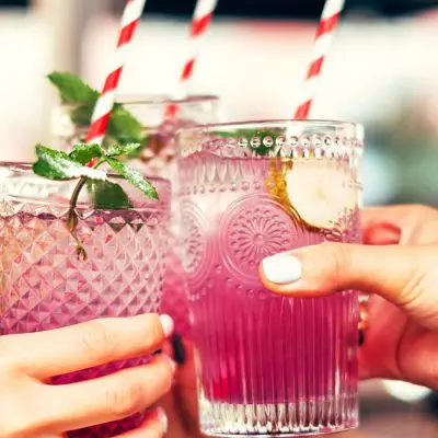 Hands clinking together pink spring cocktails