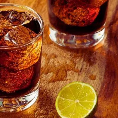 A Vodka and Coke cocktail served on ice with a twist of lime