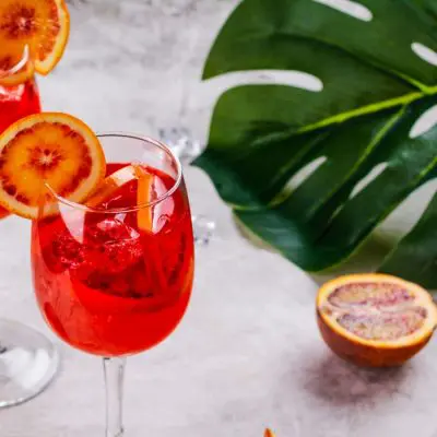 Two bright red Campari Spritz cocktails with blood orange garnish