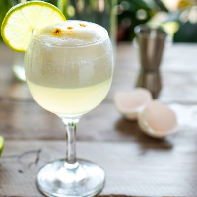 Gin Sour with a white foamy top and lime wheel garnish