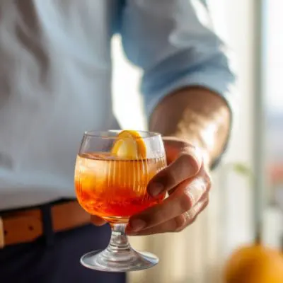 Close up of a man in a button-down shirt holding a Father's Day cocktail in a bright and inviting kitchen