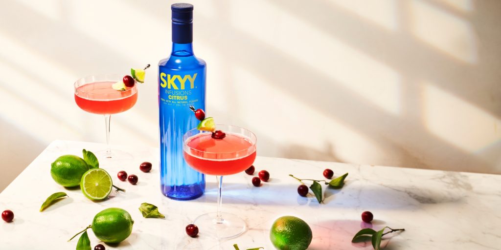 Two SKYY Vodka Cosmopolitans with a bottle of SKYY Vodka Citrus next to them 