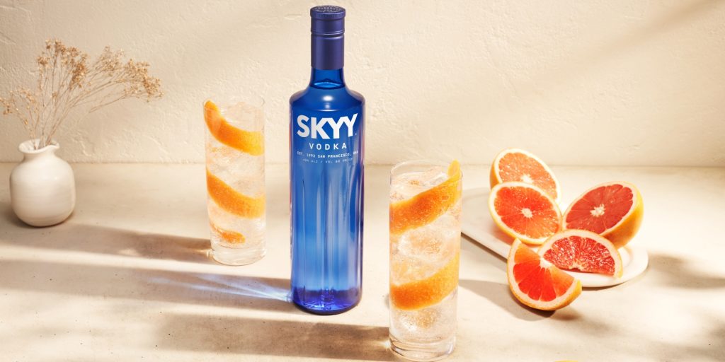 Two SKYY Vodka Soda cocktails with grapefruit peel garnish and a bottle of SKYY Vodka 