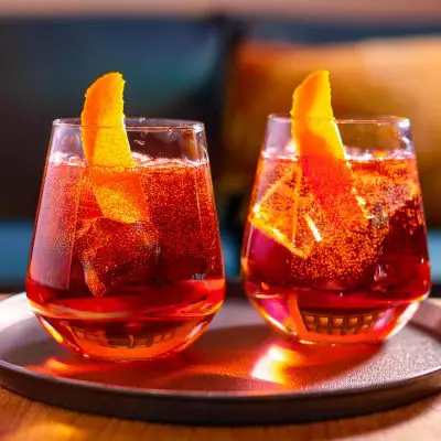 Two bright red Bicicletta cocktails with orange twist garnish