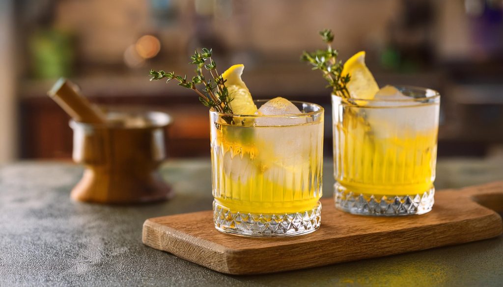 Close-up of two White Negroni cocktails with lemon and thyme garnish