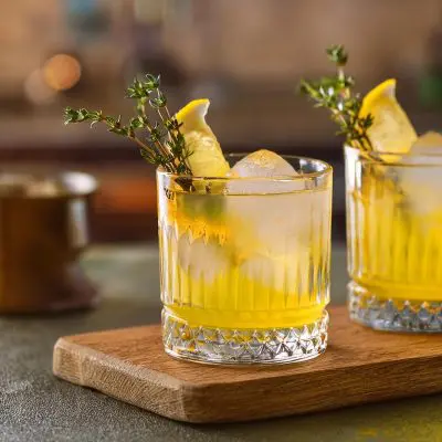 Close-up of two White Negroni cocktails with lemon and thyme garnish