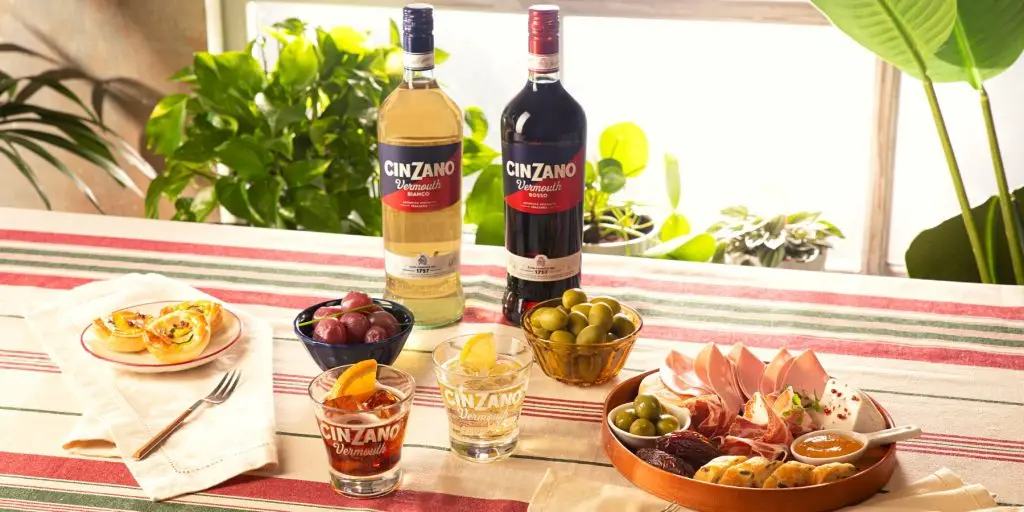 Cinzano Vermouth Bianco and Rosso bottles displayed side by side, with a dark and elegant background.