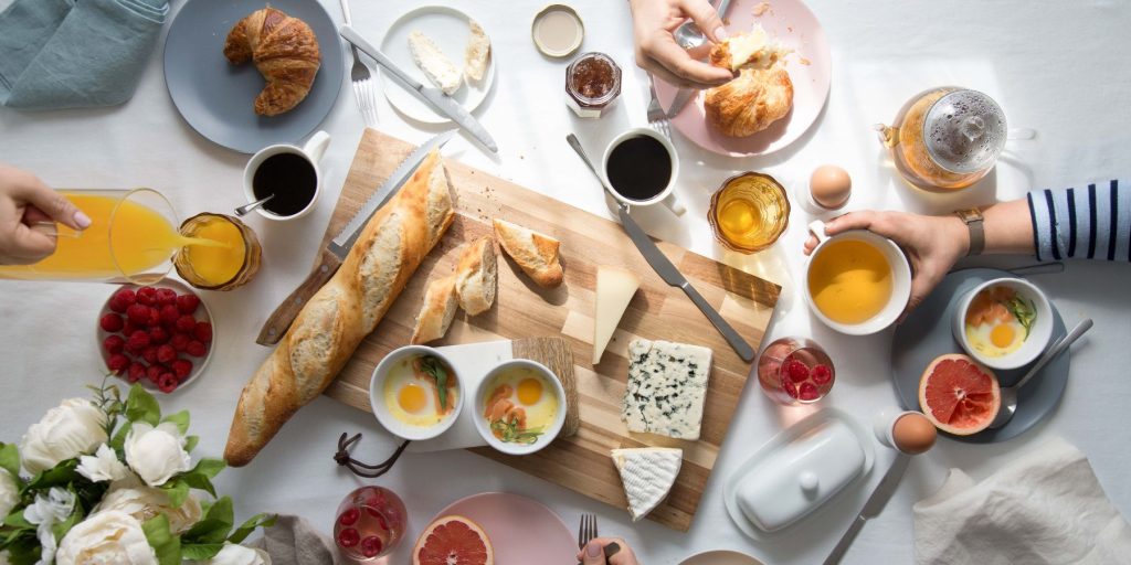 Top view of a group of friends enjoying brunch mocktails and a array of tasty breakfast foods