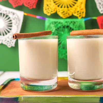 Two Horchata cocktails with cinnamon garnish in a Cinco de Mayo party setting