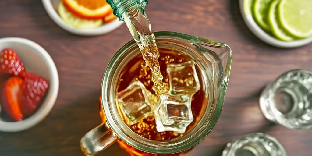 A top-view of vodka being poured into a jug of iced tea