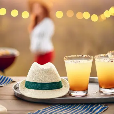 A tray of Margarita summer batch cocktails served with chargrilled corn at a barbecue at sunset