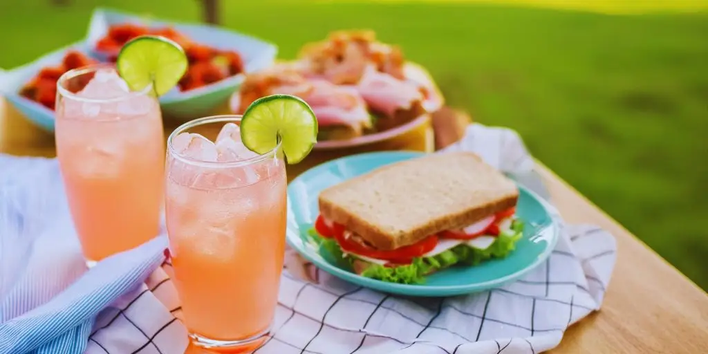 Two Strawberry Daiquiri Spritz summer mocktails served with sandwiches at a garden party