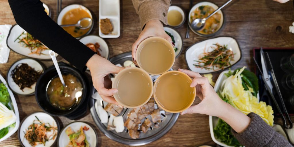 Friends enjoying Korean rice wine alongside a variety of tasty Korean dishes