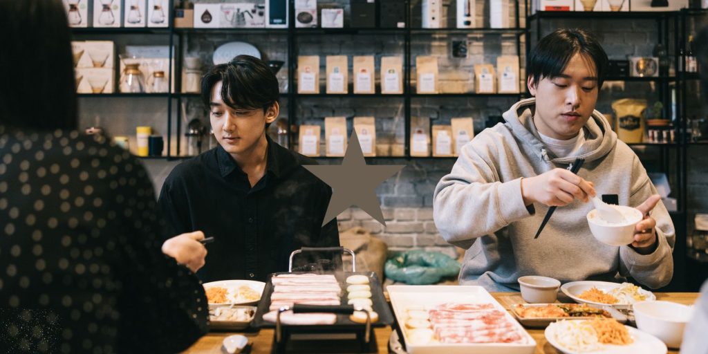 Japanese and Korean friends enjoying Korean BBQ in a cozy cafe environment