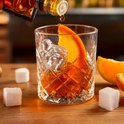 Close-up of bitters being added to an Old Fashioned cocktail