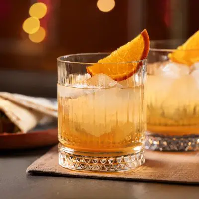 Close up of two Montelobos Mezcal Old Fashioned cocktails with orange wedge garnish