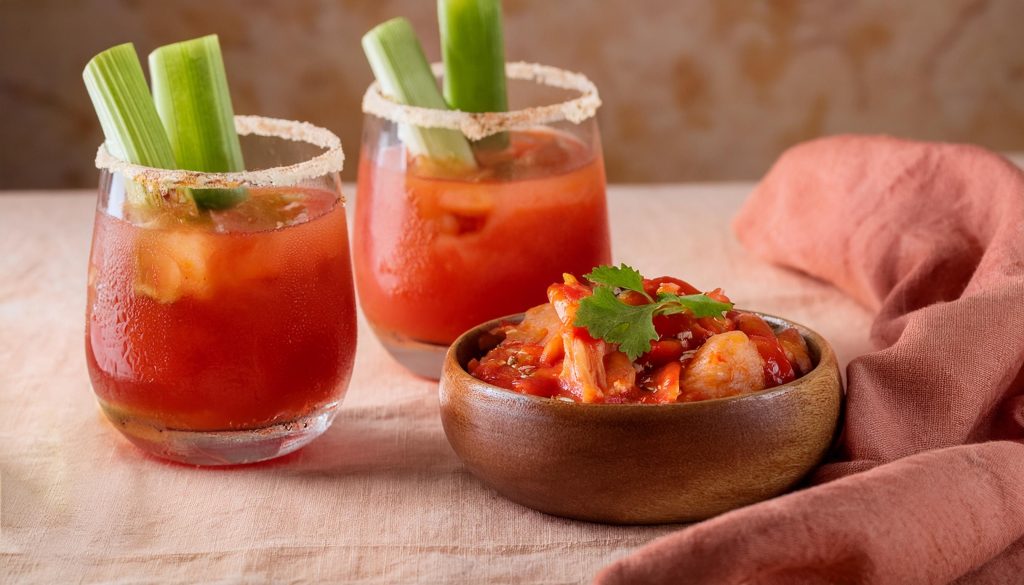 Two Kimchi Bloody Mary cocktails next to a bowl of kimchi