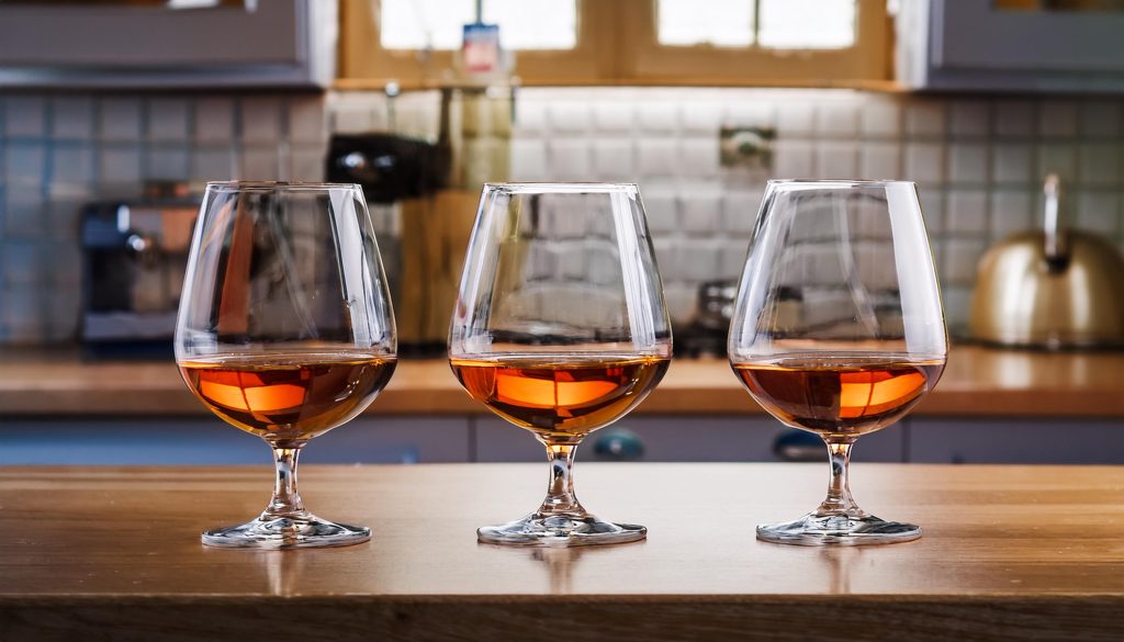 Three glasses of Armagnac next to one another, modern French kitchen setting 