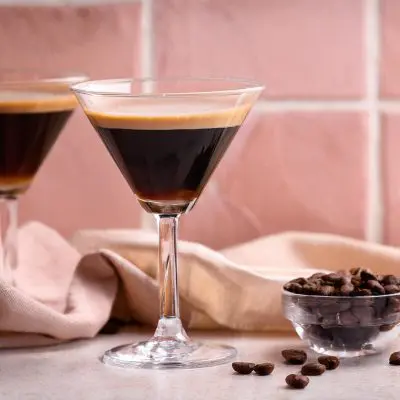 Two Cinnamon Espresso Martinis styled against a pale pink tiled background