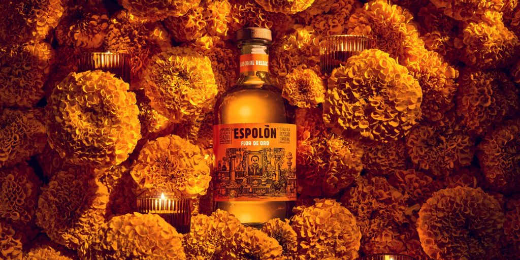 A flat-lay design of a bottle of Esolòn Flor de Oro nestled in marigold flowers