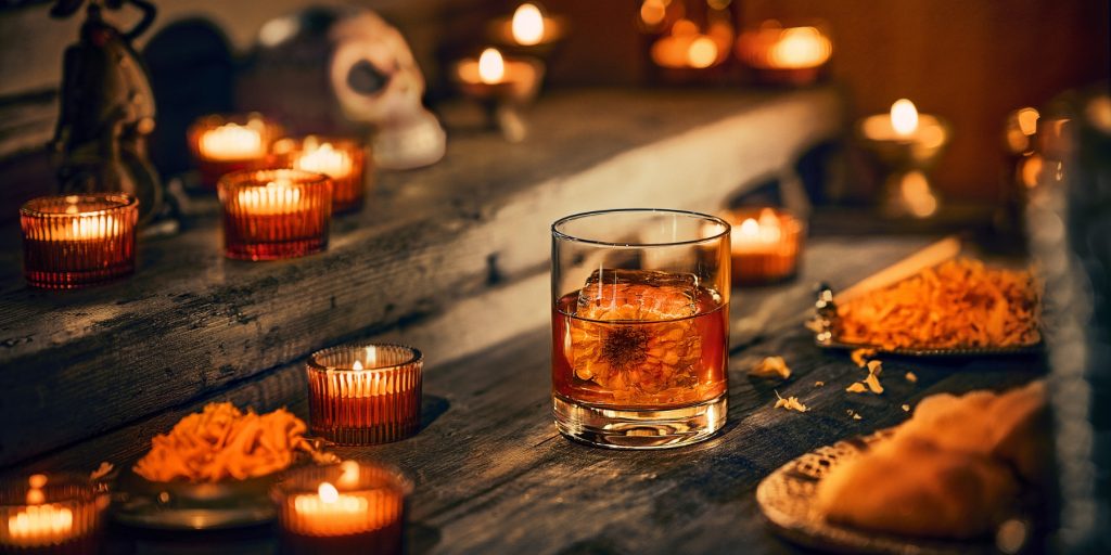 An Espolòn Flor de Oro Old Fashioned served in a rocks glass over an ice cube with a flower frozen inside the cube