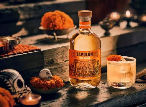 A bottle of Espolòn Flor de Oro next to a Marigold Margarita for Día de Muertos