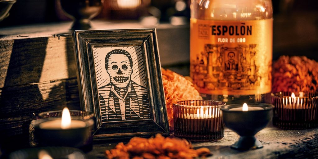 A bottle of Espolòn Flor de Oro on a table with Día de Muertos décor