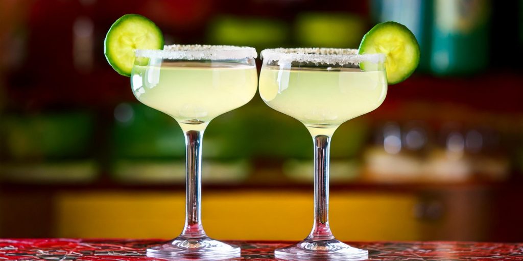 Two Mexican Razorblade cocktails served in elegant coupe glasses with cucumber garnish