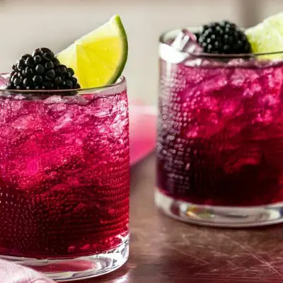 Two Blackberry Paloma Mocktails with fresh blackberry and lime garnish