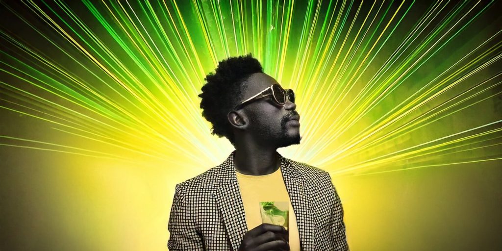 A Jamaican man holding a mojito, yellow and green lasers on the ceiling